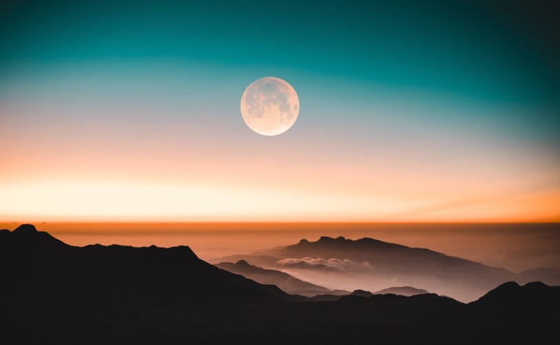 Image of the moon clear against mountain tops
